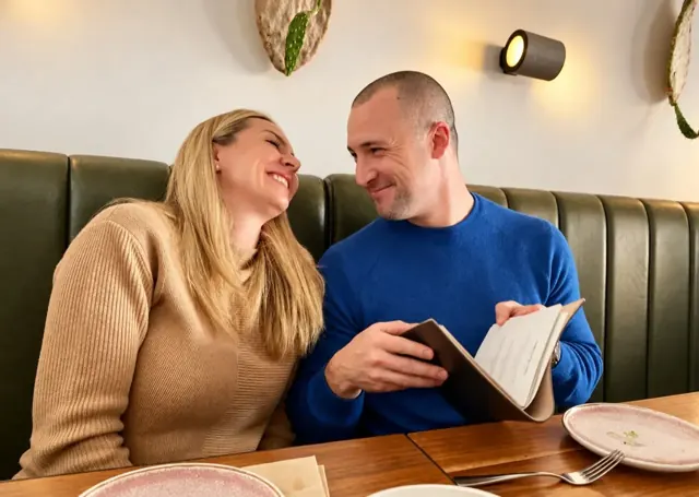 Jaq and Mike looking at each other over a book